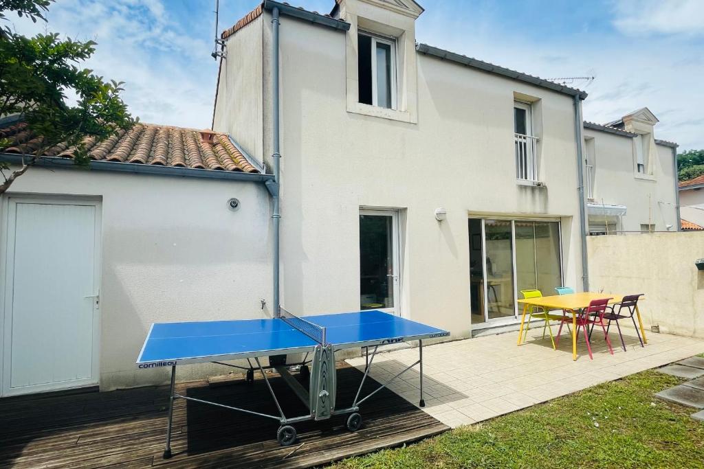 een blauwe tafeltennistafel op een terras met een huis bij Spacious house with garden in La Rochelle