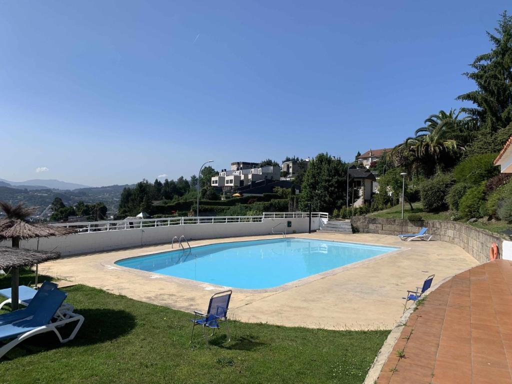 una grande piscina con due sedie blu in un cortile di Illa de tambo house a San Salvador de Poio