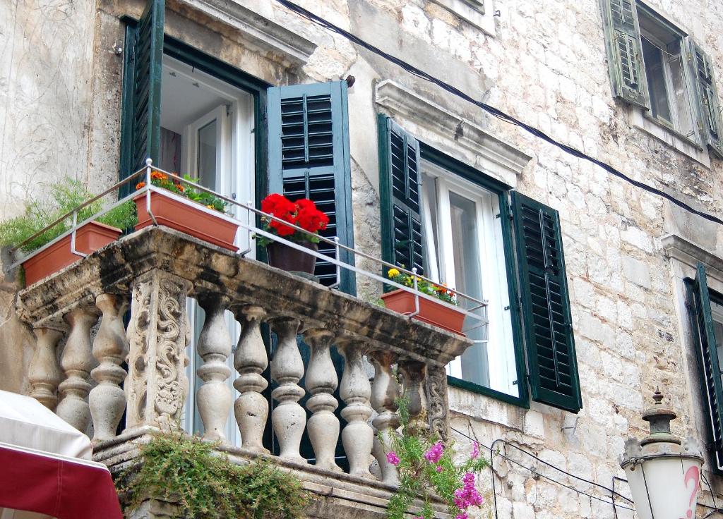 a balcony with red flowers in a window at Apartment Citadela in Split