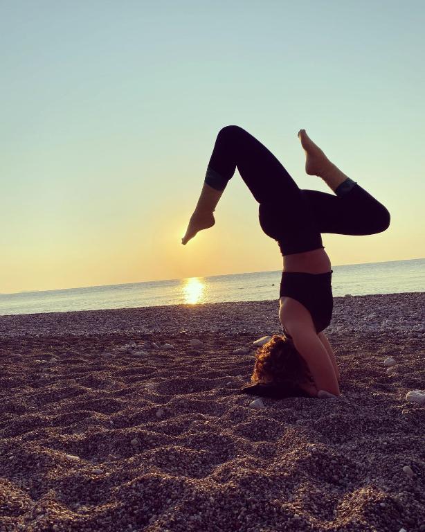 a woman doing a yoga pose on the beach at Sheriff, Olympos in Kumluca
