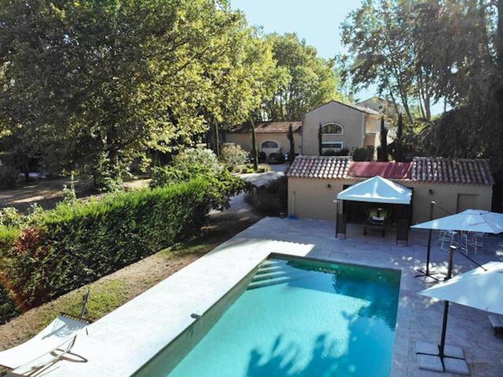 een zwembad met parasols naast een huis bij Magnifique Gîte en provence in Sarrians