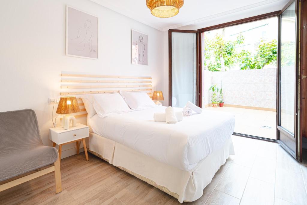 een slaapkamer met een groot wit bed en een stoel bij Apartamento Cimadevilla II in Gijón