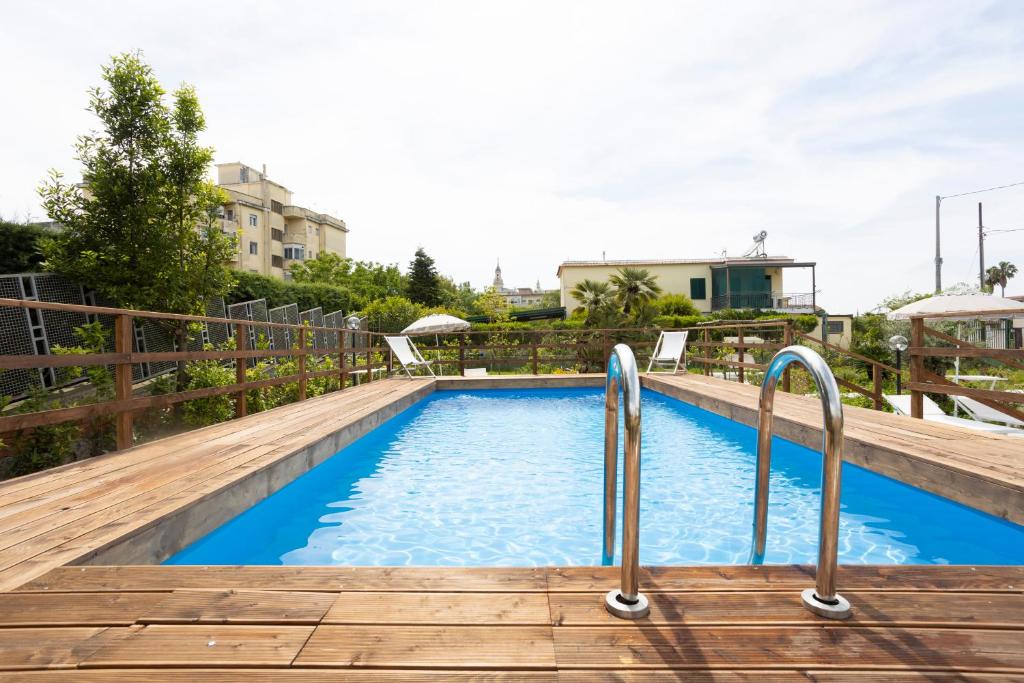 a swimming pool with blue water and a wooden deck at Residence O'Sole Mio Pompei in Pompei