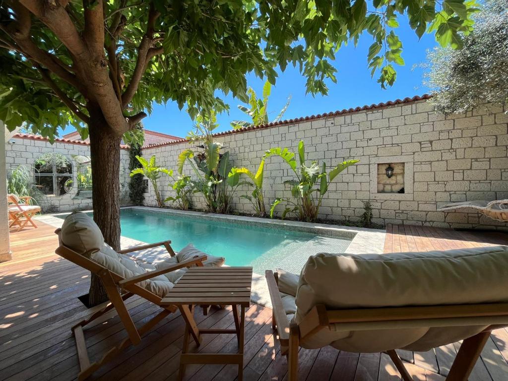 a pool with two chairs and a couch next to a tree at ARMİ BUTİK OTEL in Cesme