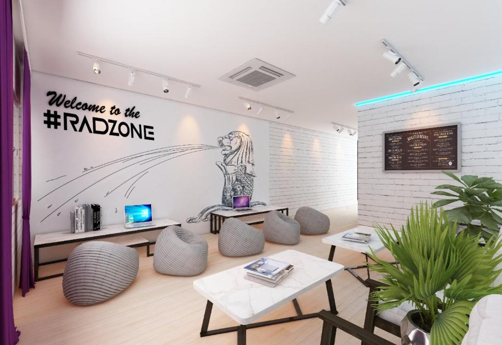 a room with tables and chairs and a wall with a sign at RadZone Hostel in Singapore