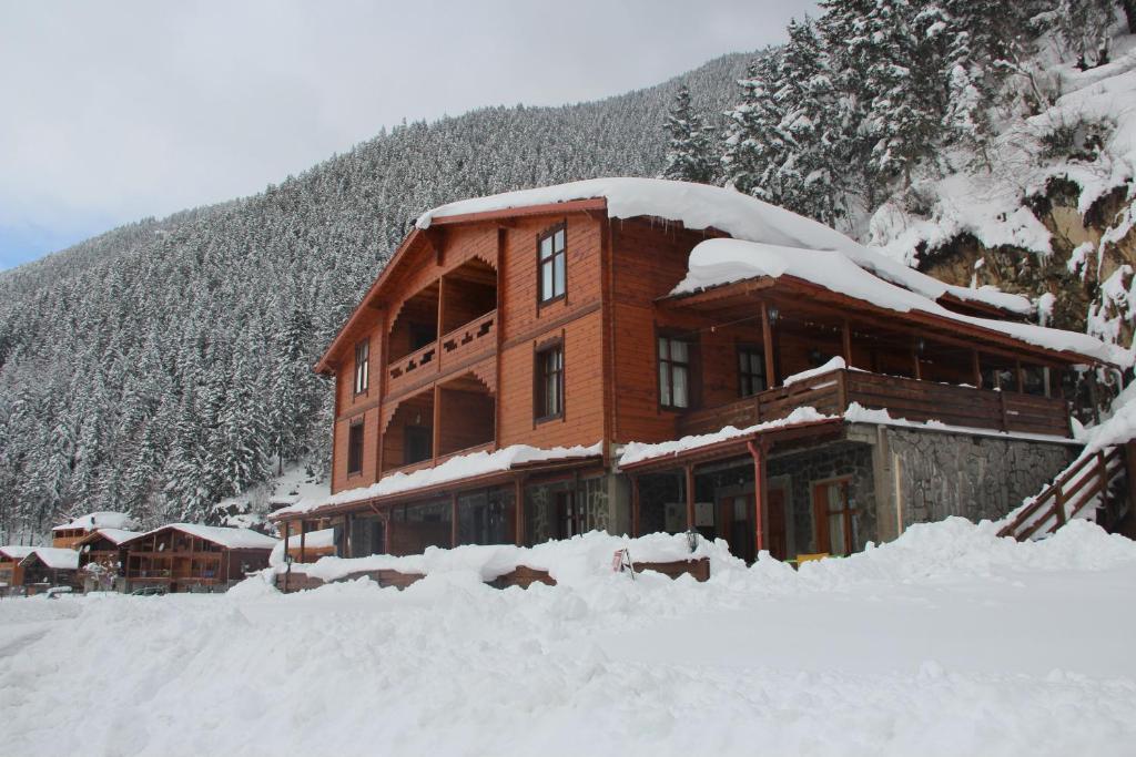 a large building covered in snow in front of a mountain at Sarahome Apart in Uzungöl