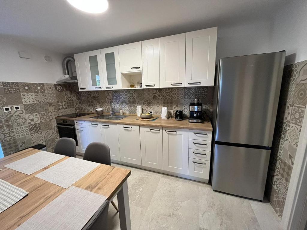 une cuisine avec des armoires blanches et un réfrigérateur en acier inoxydable dans l'établissement Apartment Hermes, à Lovran