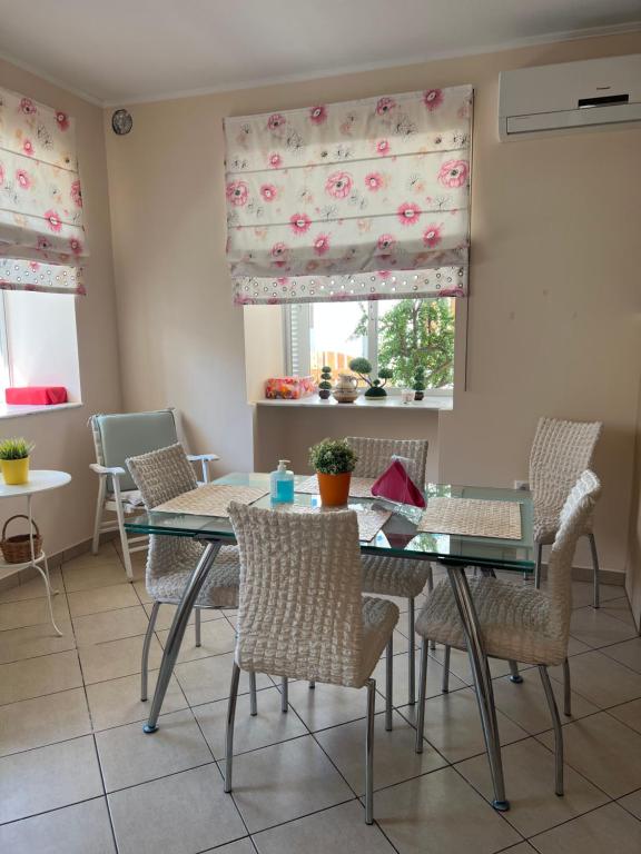 a dining room with a glass table and chairs at Maria's guesthouse in Batsi