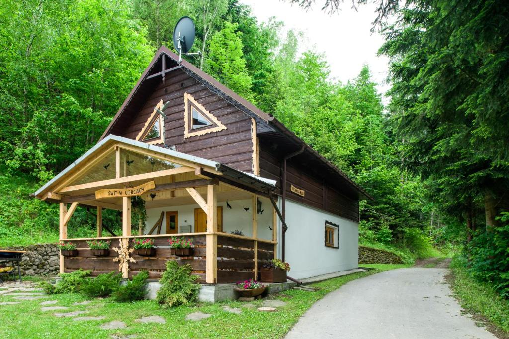 a cabin in the woods with a gambrel roof at Świt w Gorcach - dom wakacyjny in Ochotnica Dolna
