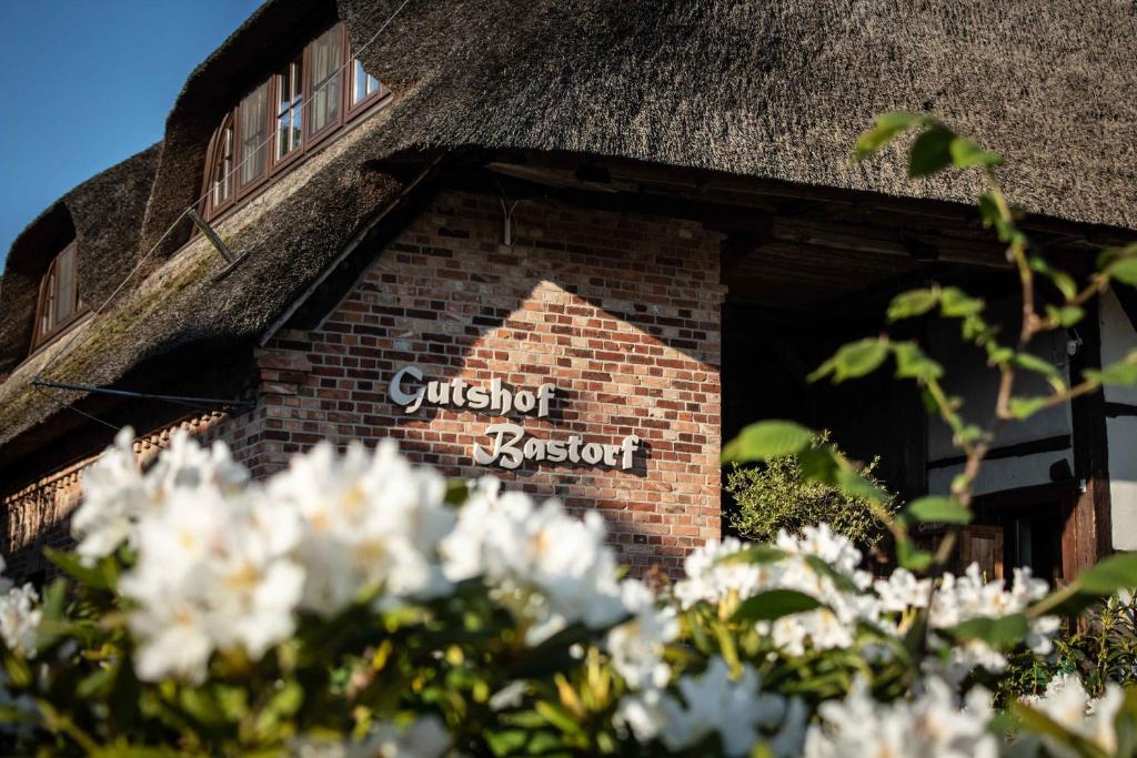 ein Schild an der Seite eines Backsteingebäudes mit weißen Blumen in der Unterkunft Gutshof Bastorf in Kühlungsborn