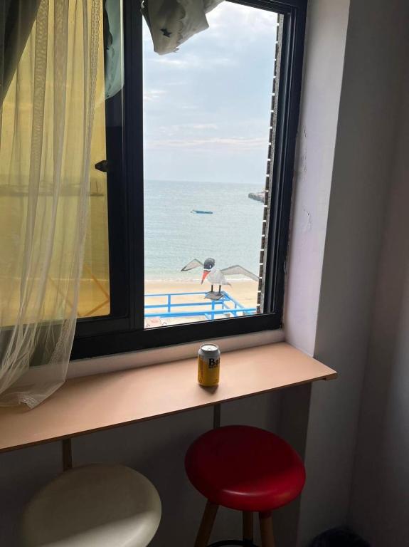 a window with a view of a beach with a red stool at Taipei Homestay in Juguang
