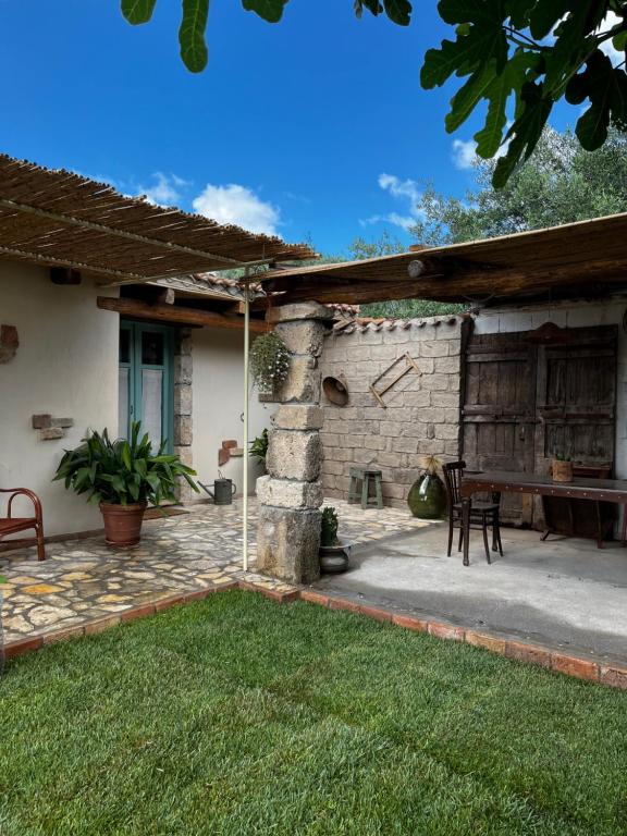 a patio with a table and a stone wall at Graziosa stanza campidanese Su terzu in Oristano