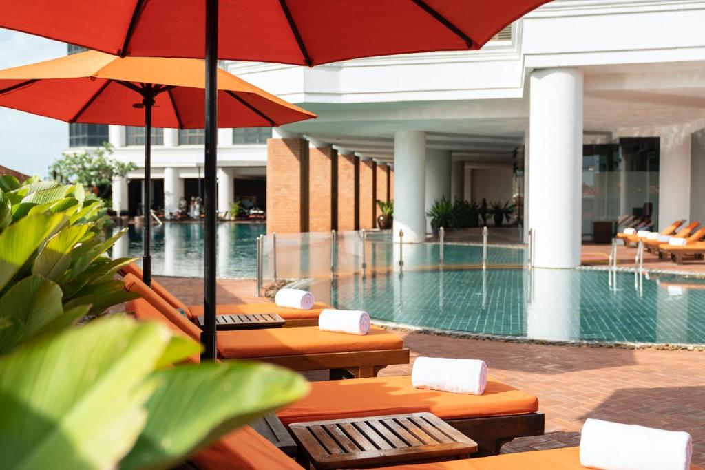 A resort-style outdoor pool framed by orange loungers and umbrellas.