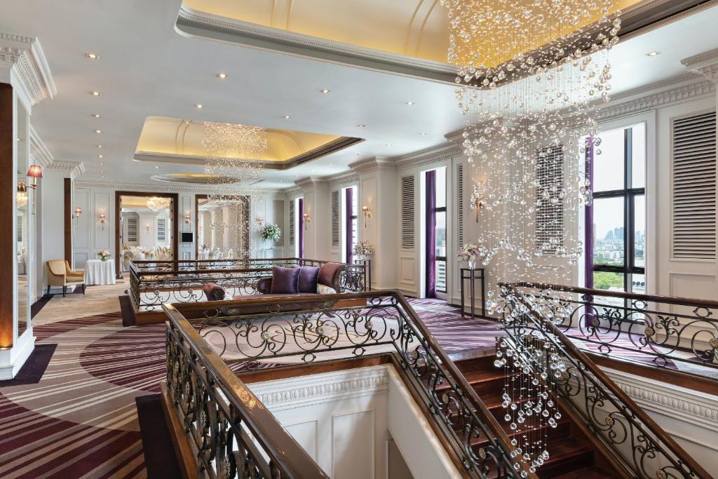 A bright, ornate lobby landing combines lounge seating with a sweeping staircase.