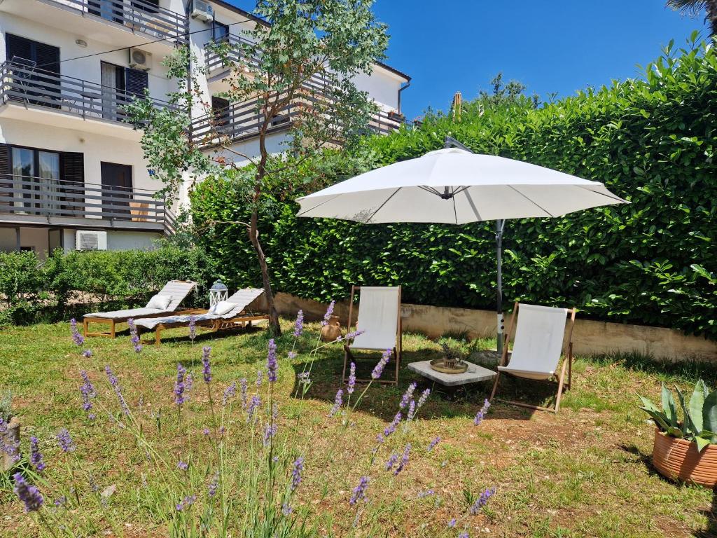 un parasol et des chaises dans la cour d'un bâtiment dans l'établissement Rooms Lav, à Umag