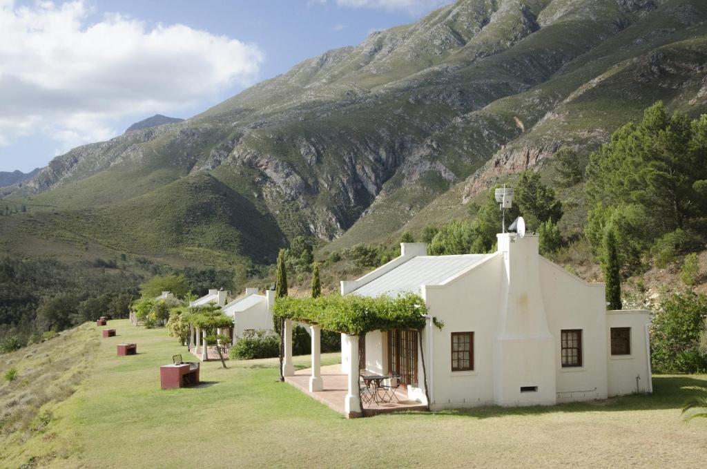 una casa blanca con una montaña en el fondo en Bushmanspad Estate, en Boesmanspad