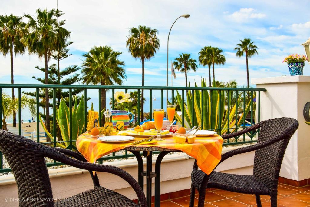 a table on a balcony with a view of the ocean at Komfortable Ferienwohnung erste Strandreihe Playa Burriana in Nerja