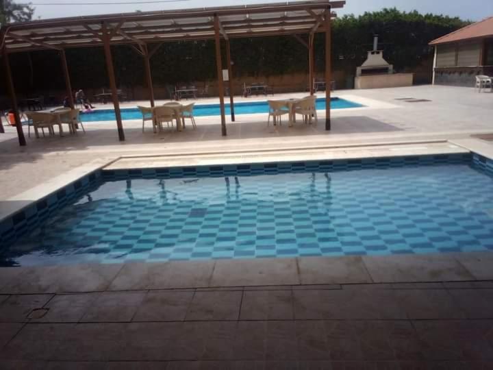 a large swimming pool with chairs and a pavilion at Dead sea 2 bedroom apartment in Astana ,swemeh Jordan in Sowayma