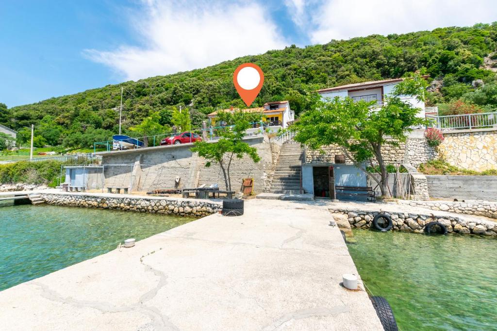 un cartello rosso posto sul bordo di uno specchio d'acqua di Apartments Luci a Rab