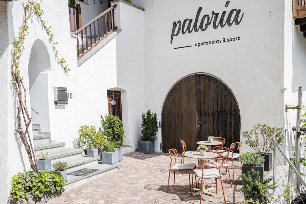 un patio con sillas y una mesa frente a un edificio en Paloria Apartments & Sport, en Lagundo