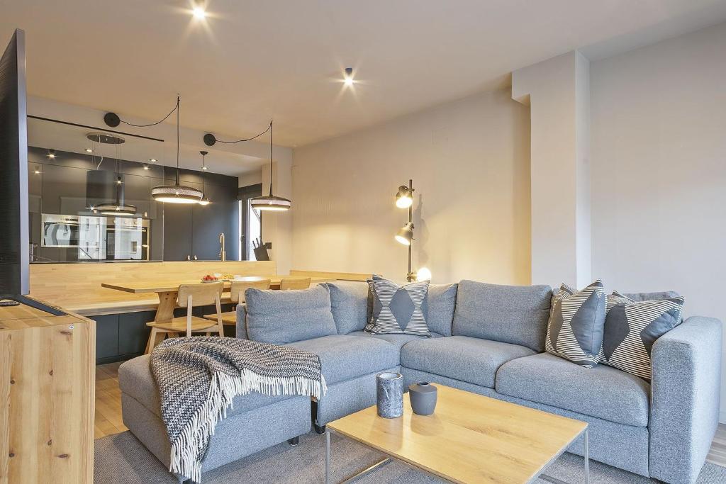 a living room with a blue couch and a kitchen at Luderna - Apartamento con terraza Montanero in Vielha