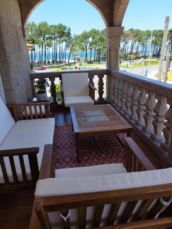 a balcony with chairs and tables and a view of a park at piso chalet en playa samil in Vigo