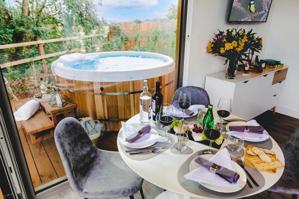 einen Tisch und Stühle mit einer Badewanne in einem Zimmer in der Unterkunft Beautiful "Stour" Eco Lodge with Private Hot Tub in East Bergholt