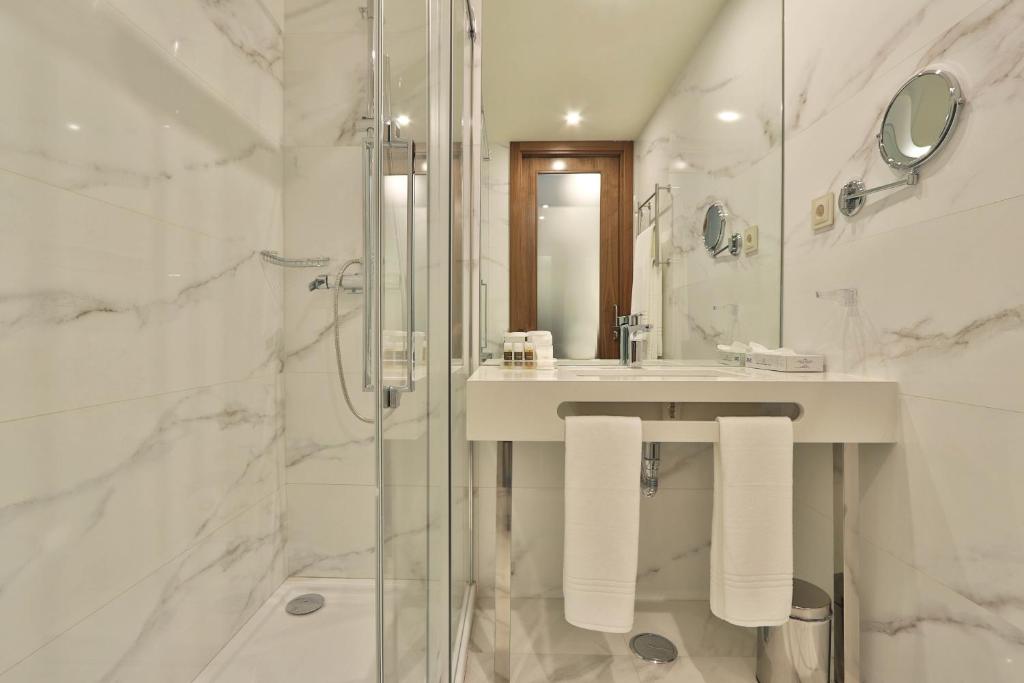 a white bathroom with a sink and a shower at TURIM Ibéria Hotel in Lisbon
