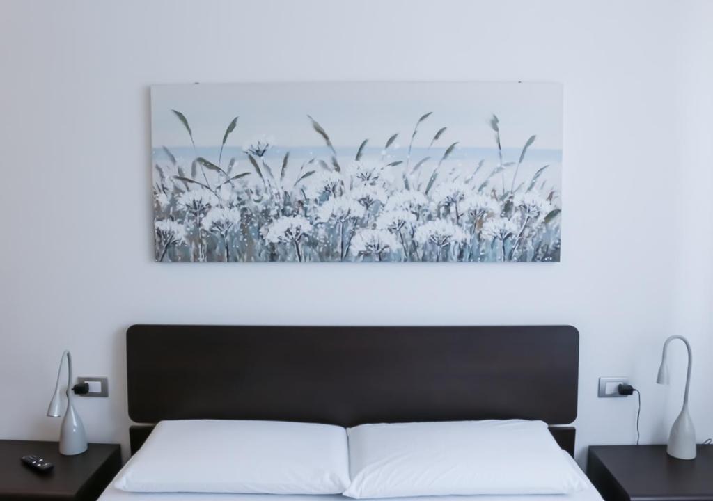 a bedroom with a bed and a painting on the wall at ATMOSPHERE 2 CENTRALE, VISTA MARE, con parcheggio in Riccione