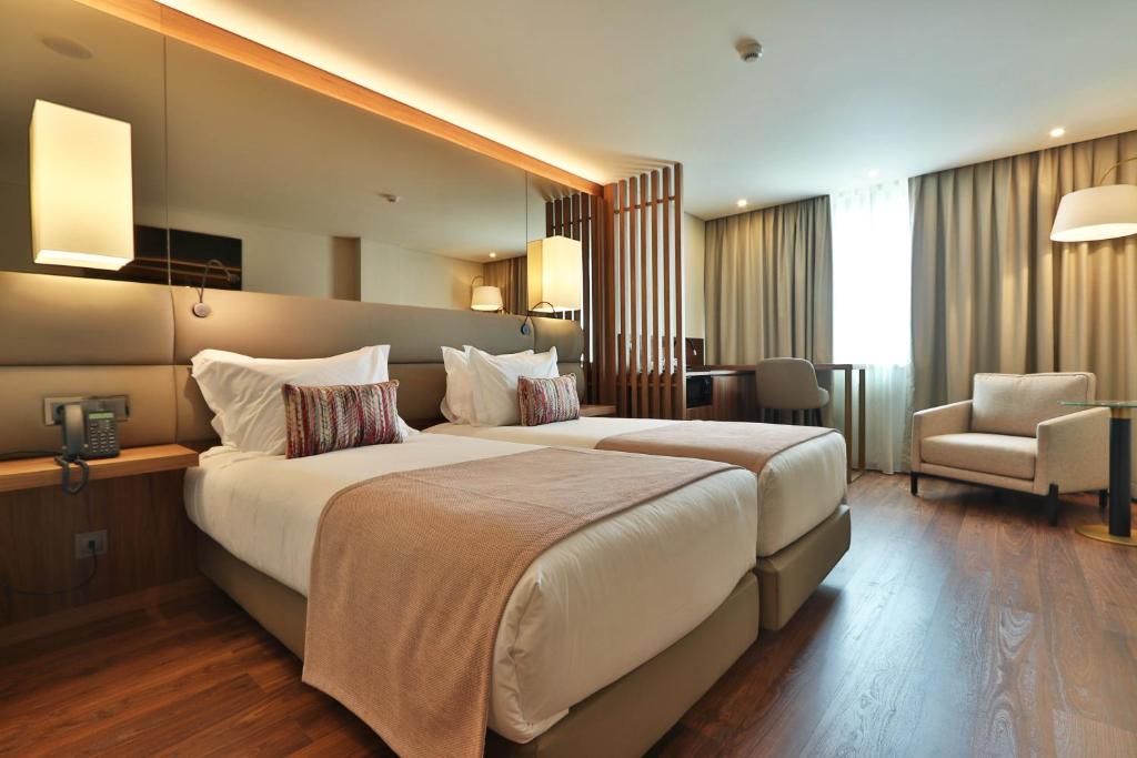 a hotel room with a large bed and a chair at TURIM Ibéria Hotel in Lisbon