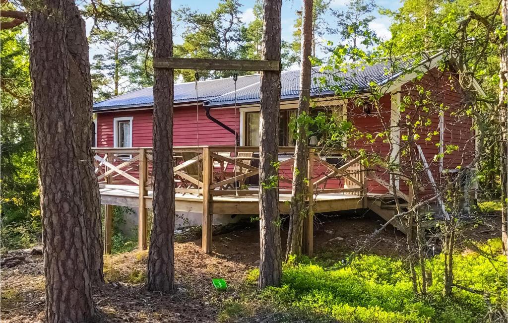 una casa roja con terraza en el bosque en 2 Bedroom Stunning Home In Norrtlje, en Norrtälje