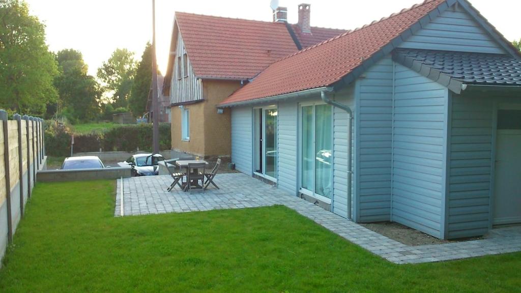 ein Haus mit einer Terrasse und einem Tisch im Hof in der Unterkunft Le GITE DU VILLAGE in Franleu