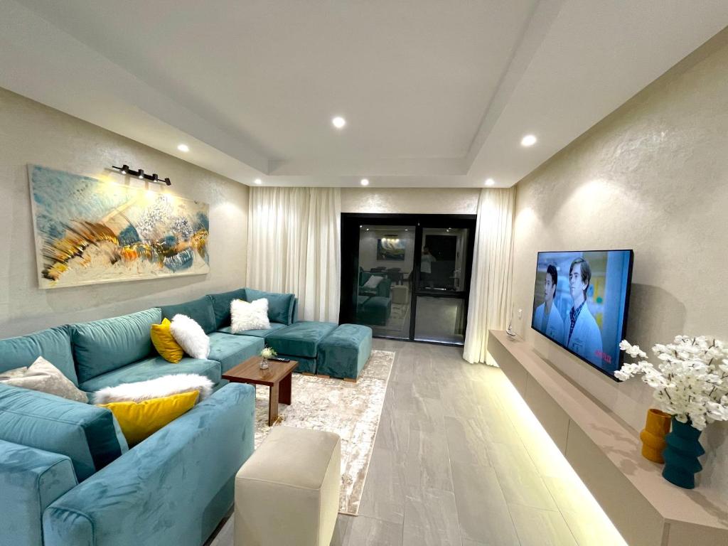 een woonkamer met een blauwe bank en een tv bij Blue Apartment vue sur l’océan : Taghazout bay in Taghazout