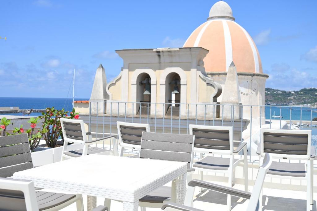 una mesa y sillas blancas con un edificio en el fondo en Don Raffaè - Luxury Apartment, en Isquia