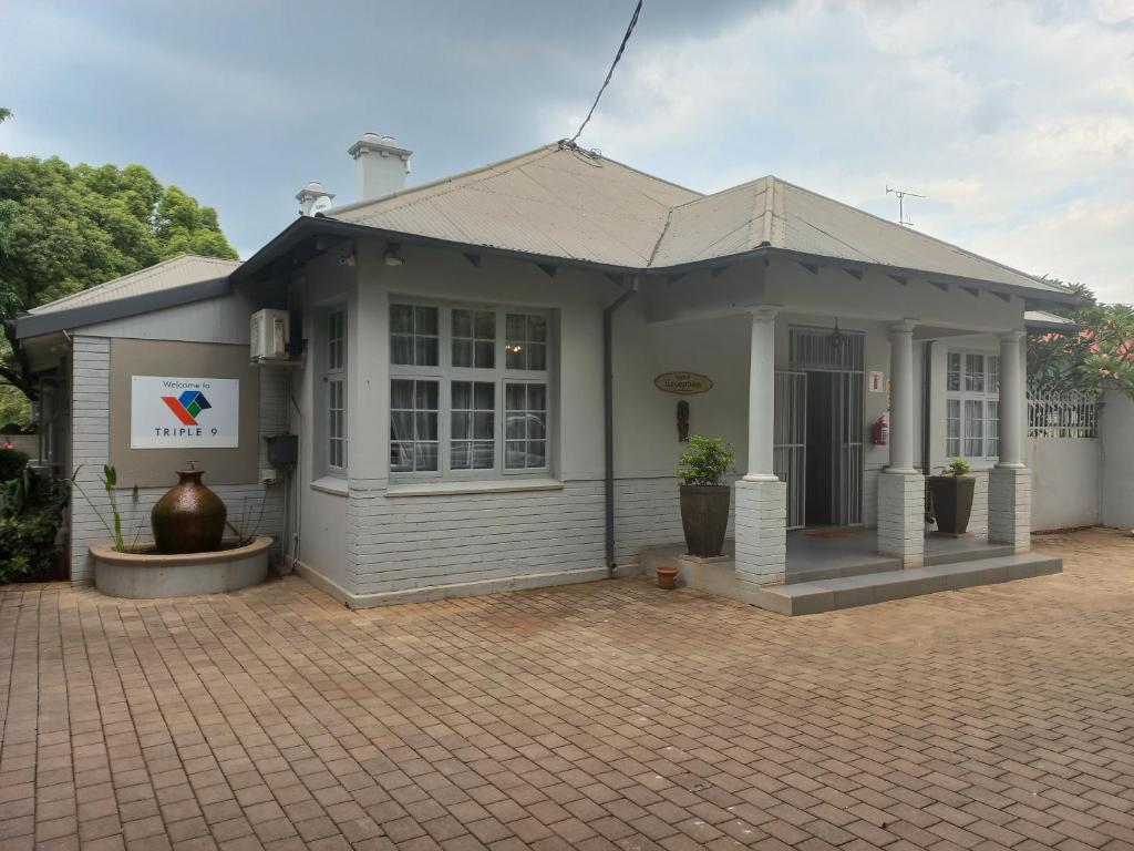 a small white house with a brick patio at Triple9 Hatfield Guesthouse in Pretoria