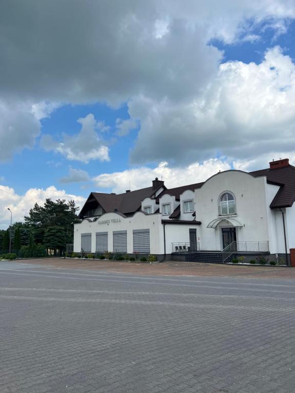 een groot wit gebouw aan de kant van een weg bij Garden Villa in Busko-Zdrój