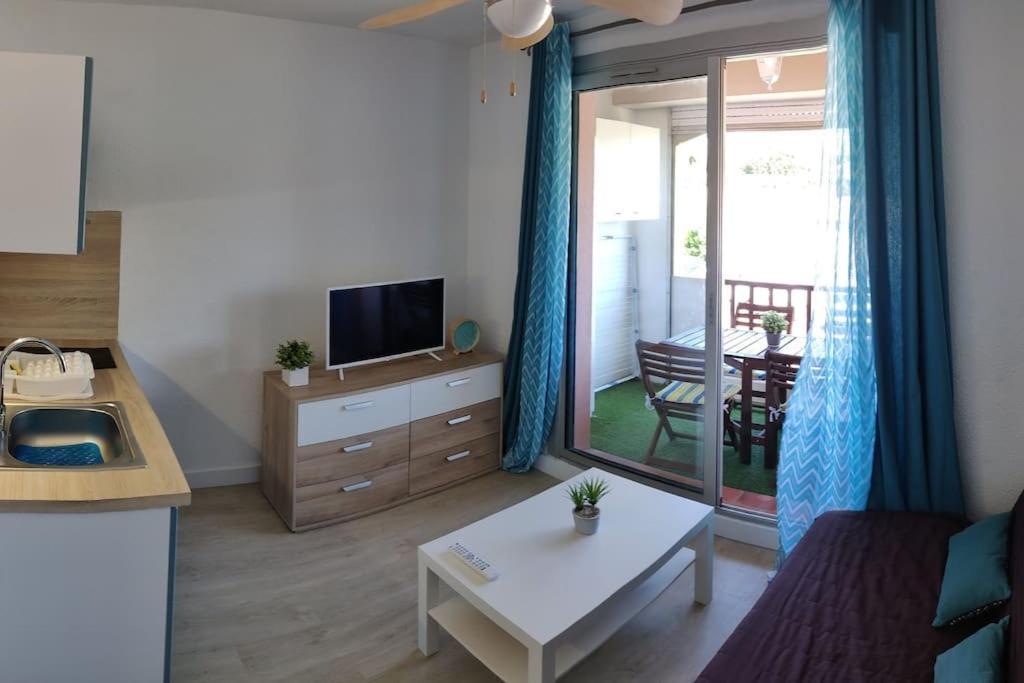 un salon avec un canapé, une télévision et une table dans l'établissement Super studio pour 4 à proximité des plages, à Sausset-les-Pins