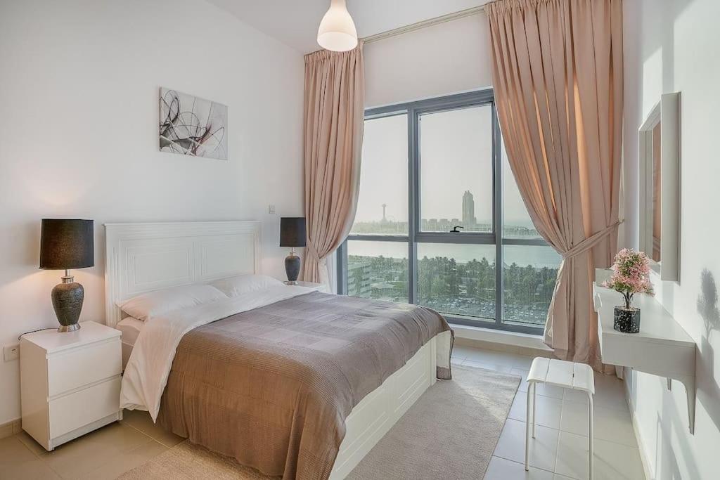 LOVELY 2 Bedroom Apartment (Sea View) في أبوظبي: غرفة نوم بسرير ونافذة كبيرة