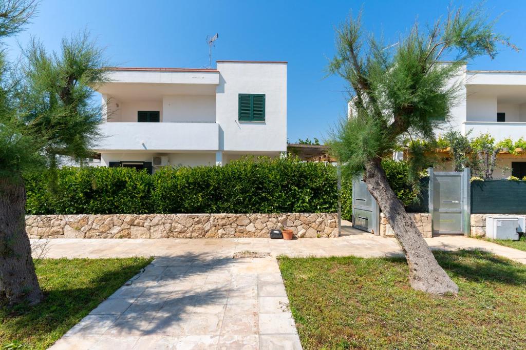a house with a stone wall and two palm trees at Villa Dalila by BarbarHouse in Torre Inserraglio