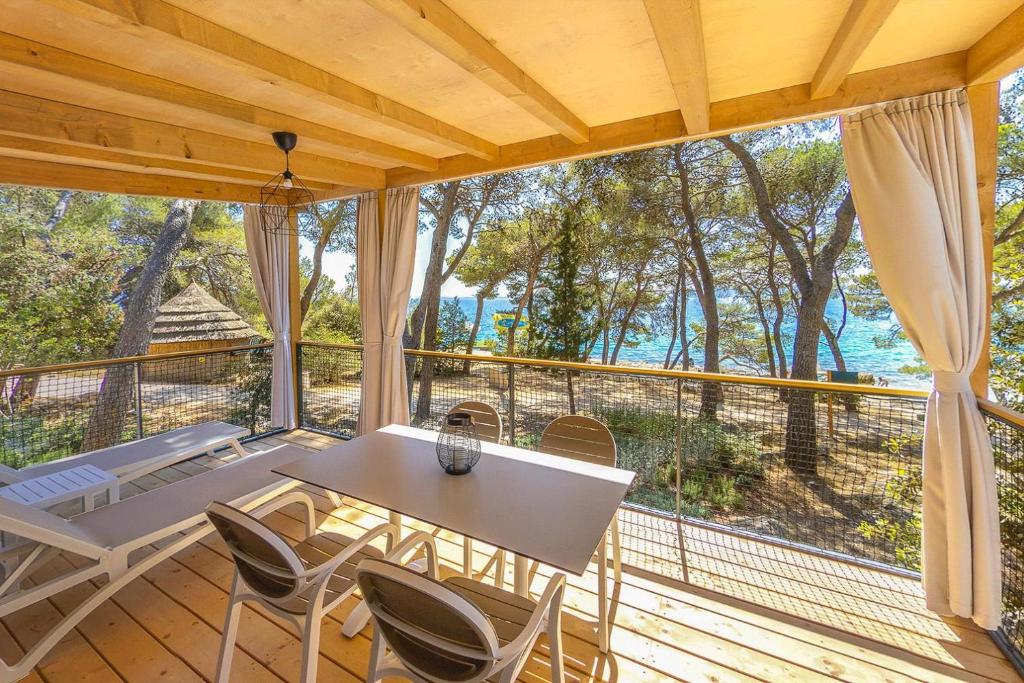 a room with a table and chairs on a balcony at Pine Beach Pakostane Glamping Homes - All Inclusive light in Pakoštane