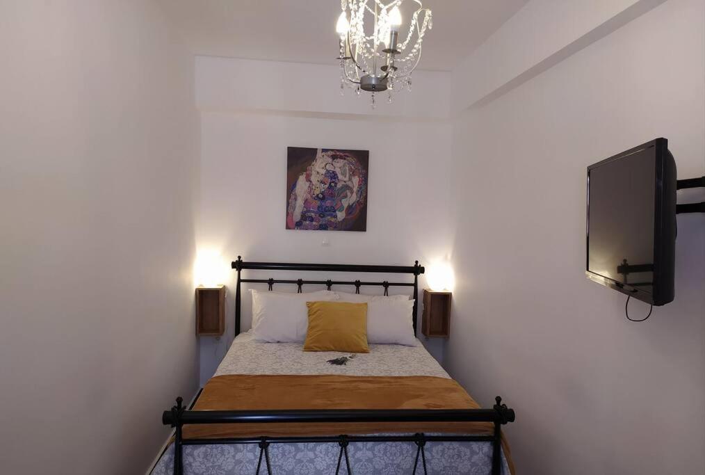 a bedroom with a bed with a television and a chandelier at Xenofon's cozy apartment in Corfu