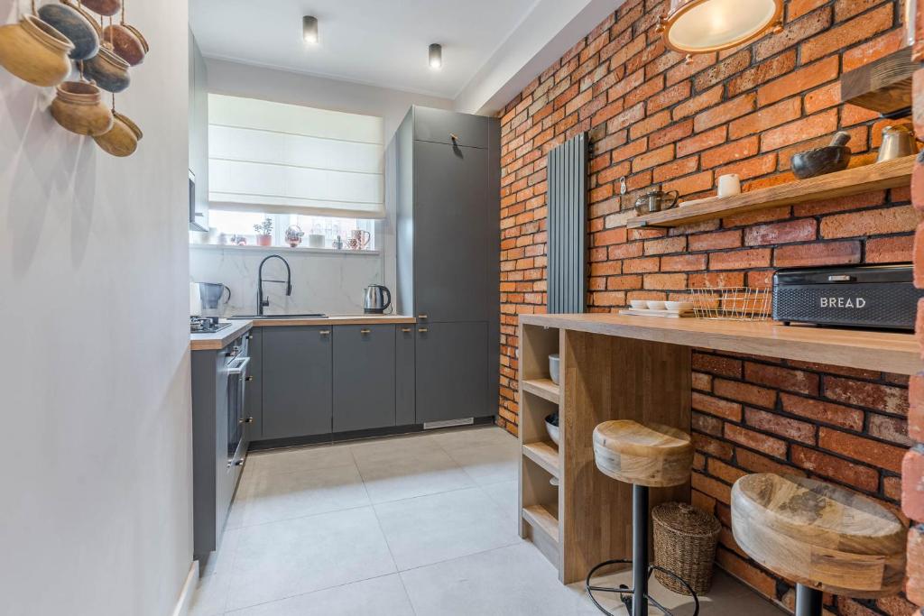 a kitchen with a brick wall at Apartament przy Stajennej in Gdańsk