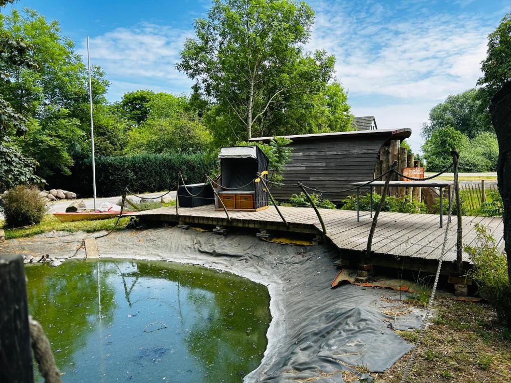 eine Holzbrücke über einen Teich im Hof in der Unterkunft Ferienwohnungen Poppelvitz in Altefähr