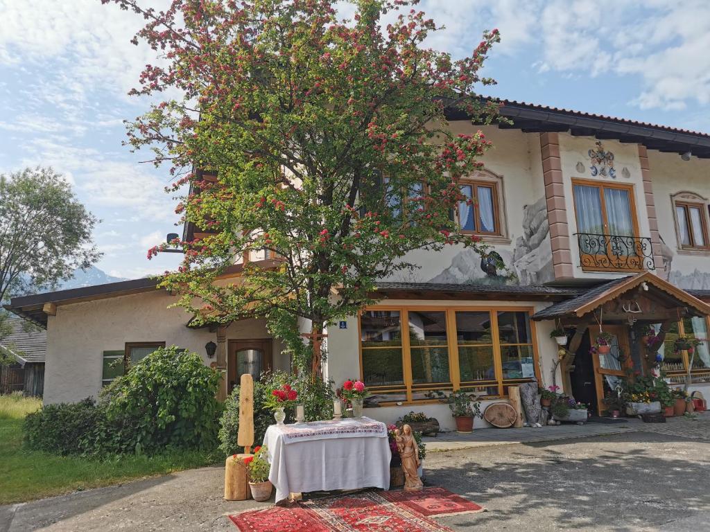 una casa con una mesa delante de un árbol en Ferienwohnungen Berghof, en Krün