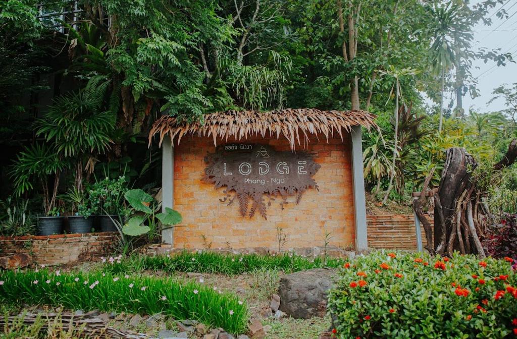 a sign on a brick wall in a garden at ลอดจ์พังงา บูทีค in Phangnga