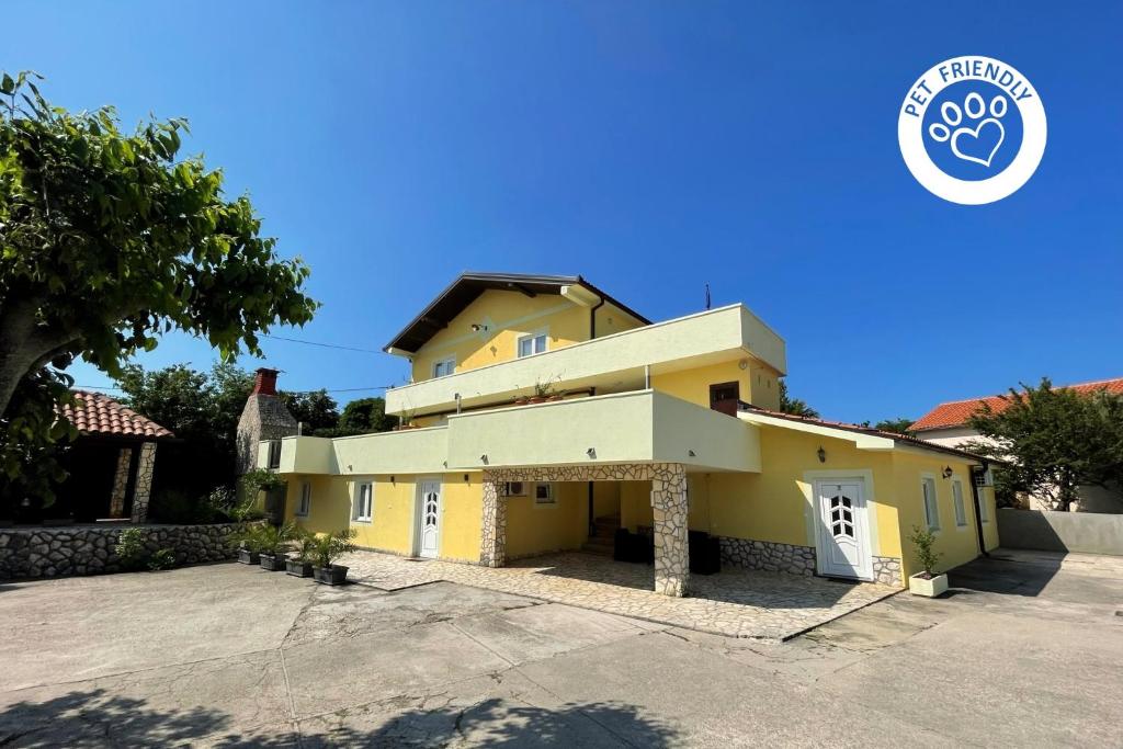 une maison jaune avec une allée devant elle dans l'établissement Top Apartments, à Šilo