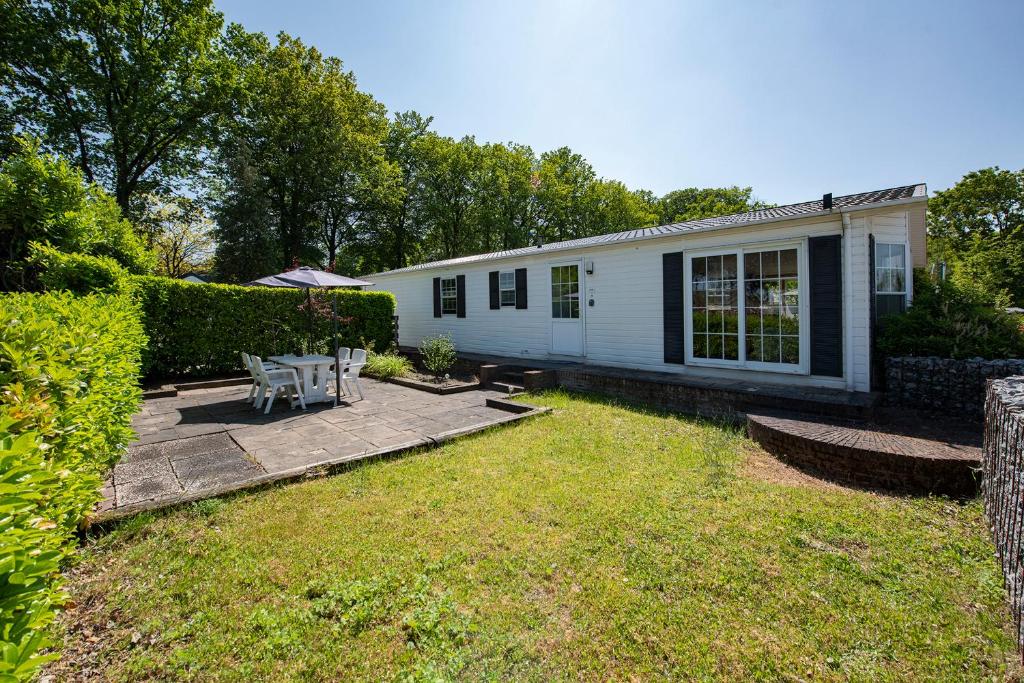 een klein wit huis met een patio in de tuin bij 79, Ruime chalet aan de Kampina in Oisterwijk
