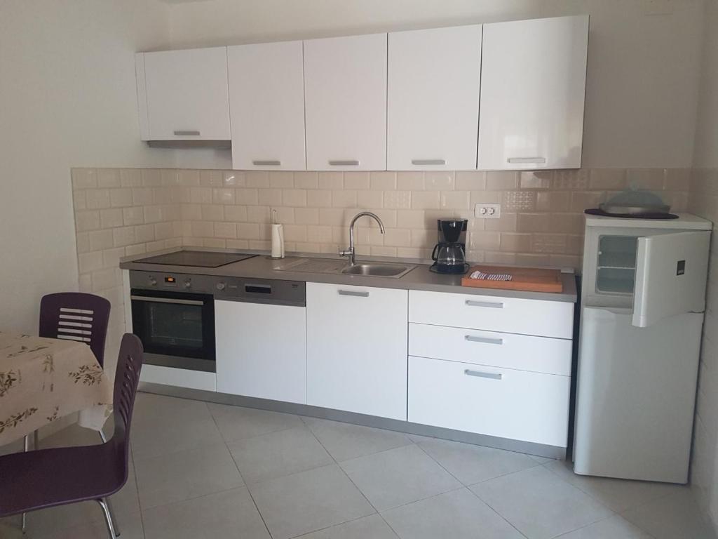 a kitchen with white cabinets and a sink and a refrigerator at Holiday home in Milna with terrace, air conditioning, WiFi, washing machine 5123-1 in Milna