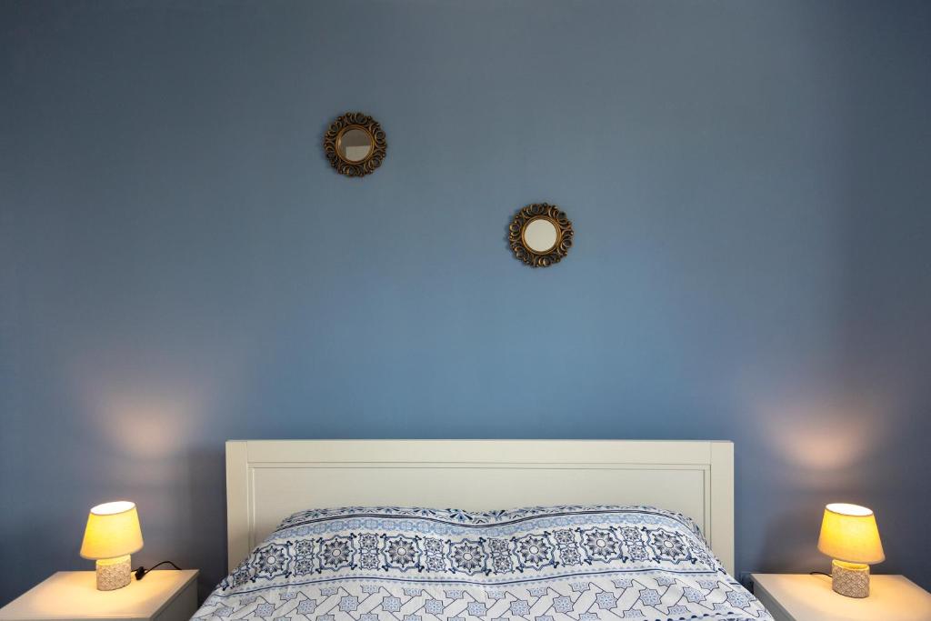 1 dormitorio con una pared azul, 1 cama y 2 lámparas en Casa via materdomini, en Brindisi