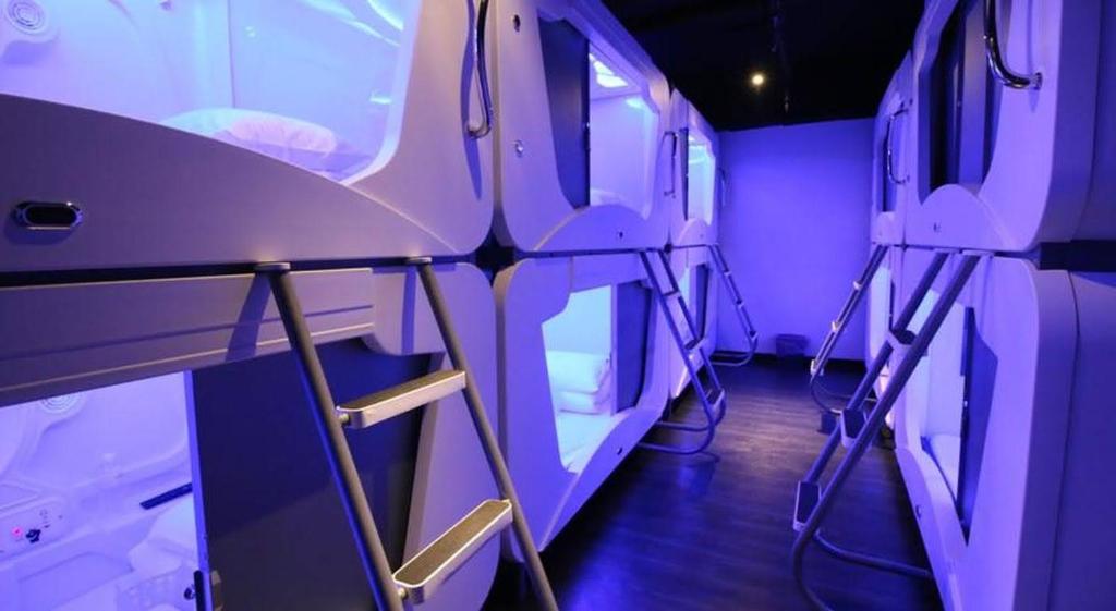 a room with purple lighting and a row of beds at Hey Bear Capsule Hotel in Taipei